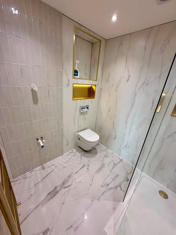 Marble-effect tiled shower room with a recessed illuminated niche and wall-hung toilet.